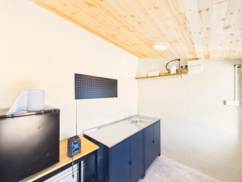 Workshop or garage interior with wooden ceiling, blue workbench, and dark storage cabinet