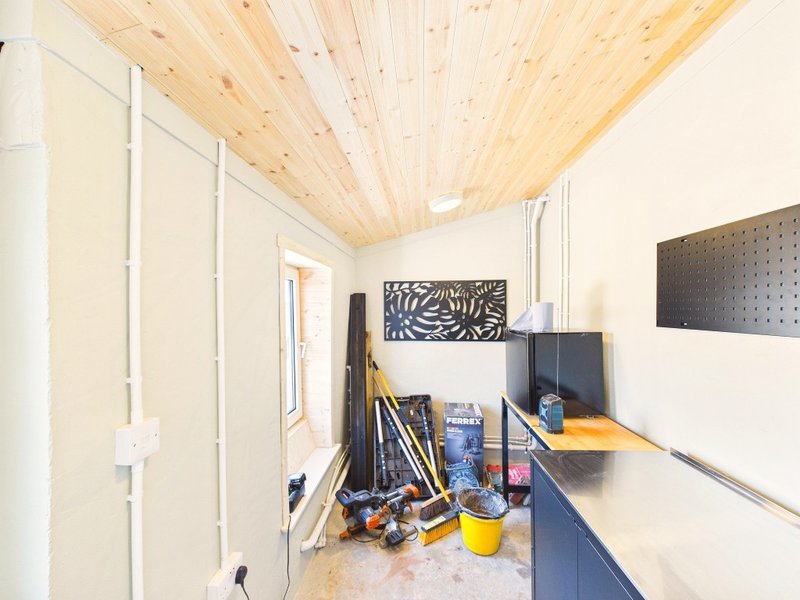Unfinished interior room with wooden ceiling, white walls, blue cabinetry, and construction materials