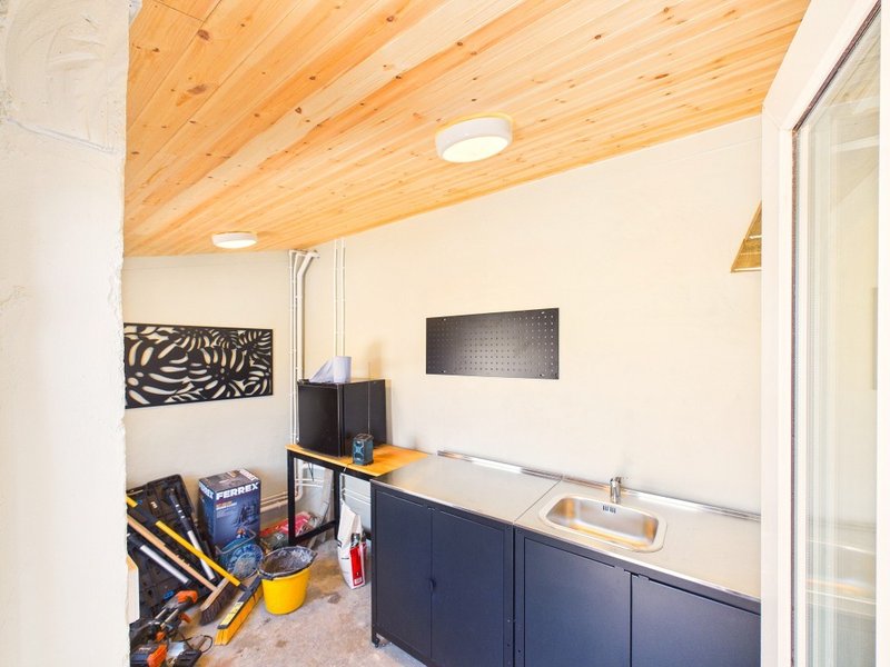 Utility room with wooden ceiling, navy cabinetry, sink, and storage shelves