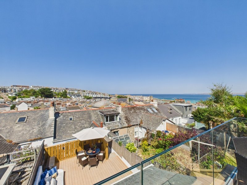 Elevated terrace with wooden decking overlooking coastal town and blue sea