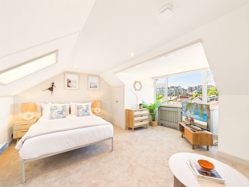 Bright loft bedroom with double bed, wooden furniture, large window with city view