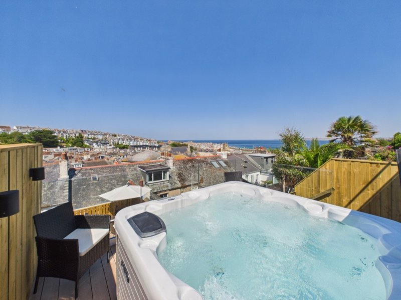 Hot tub on rooftop terrace with coastal town and sea views