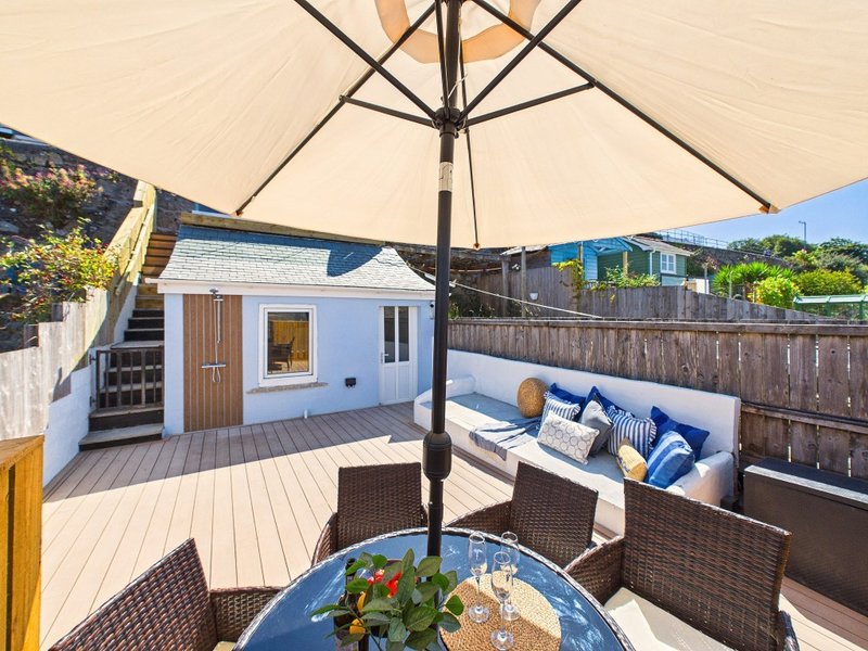 Spacious rooftop terrace with patio furniture, blue cushioned seating, umbrella and garden views