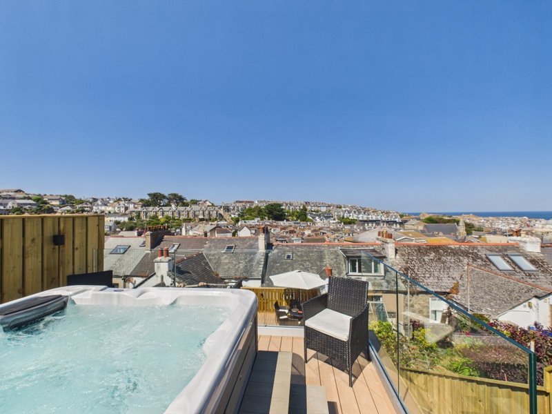 Rooftop terrace with hot tub, wooden decking, seating, and panoramic city views