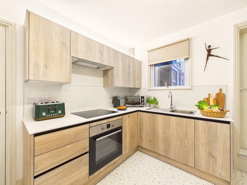 Modern kitchen with light wood cabinets, black countertops, stainless steel appliances and window