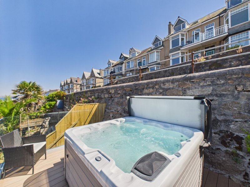Hot tub on wooden deck with stone wall and Victorian building backdrop