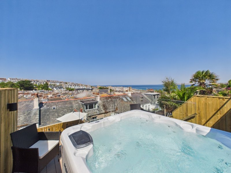 Rooftop hot tub with coastal town and sea views, wooden decking and bench seating