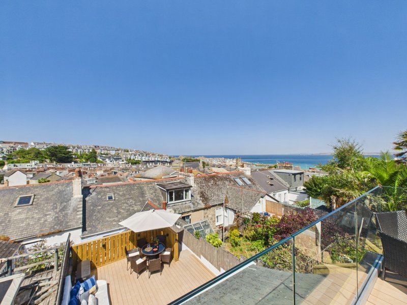 Coastal rooftop terrace with wooden deck, seating area, and sea view
