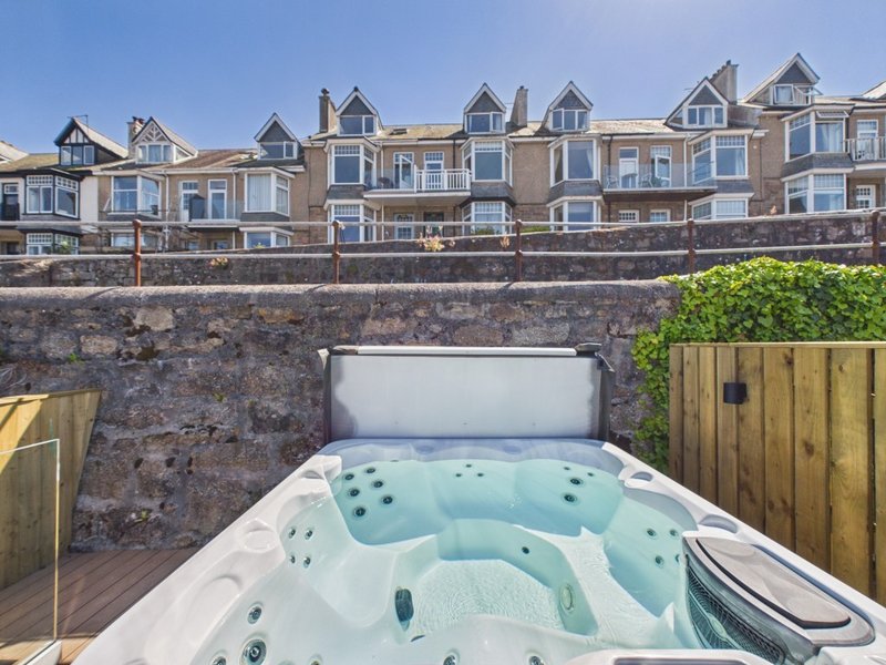 Hot tub in enclosed courtyard with stone wall and residential building beyond