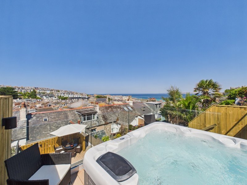 Hot tub on rooftop terrace overlooking coastal town and sea views