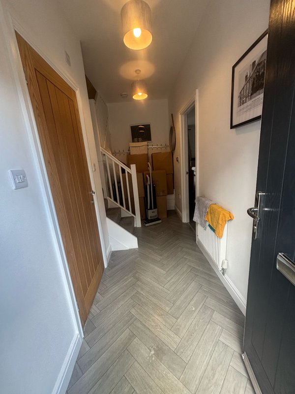 Modern hallway with herringbone flooring, pendant lights, wooden and black doors, and white walls