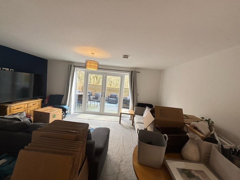 Living room with furniture, cardboard boxes, TV, and glass doors to balcony