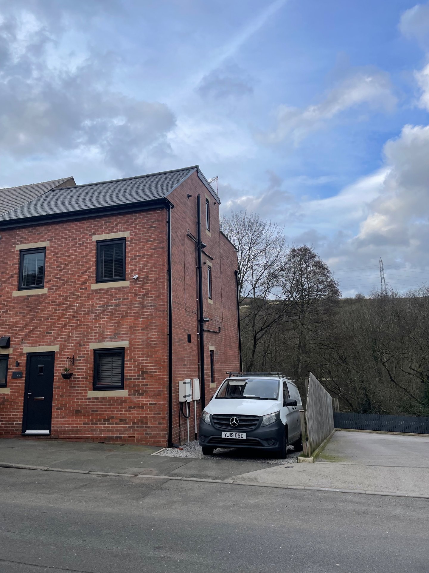 Brick exterior of modern residential property with driveway, parked van and countryside views
