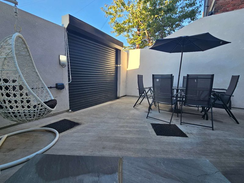 Modern patio with dining table, umbrella, chair and black roller garage door