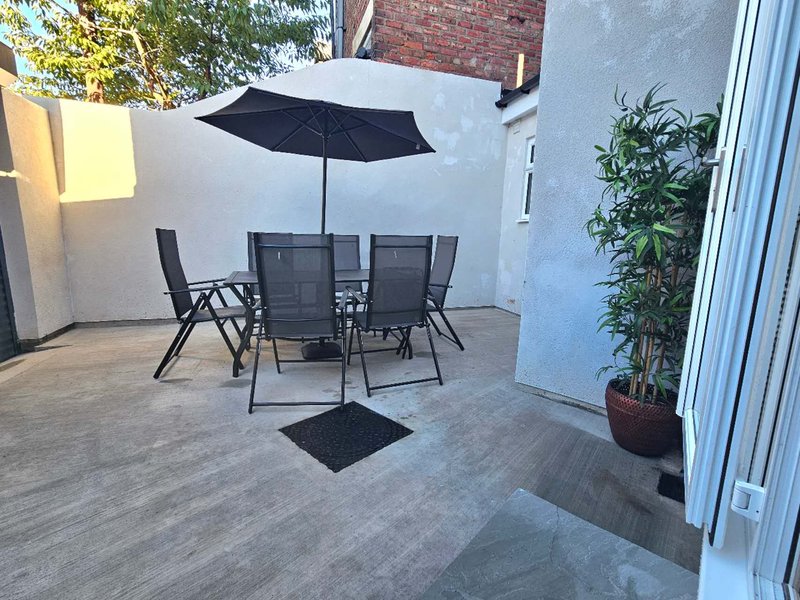 Outdoor patio with dining table, chairs, black umbrella and potted plants