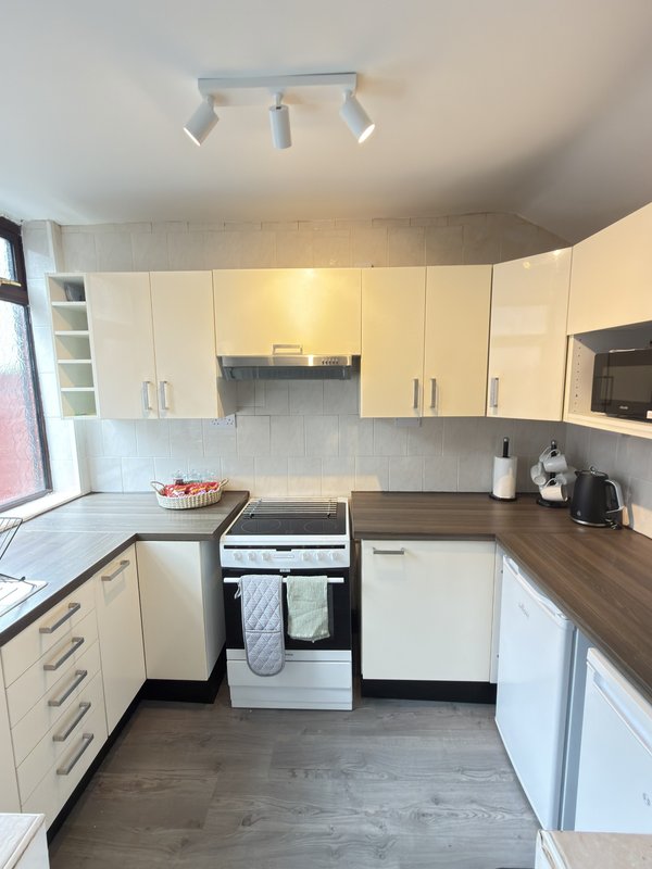 Modern kitchen with white cabinetry, wooden countertops, gas range and tiled backsplash