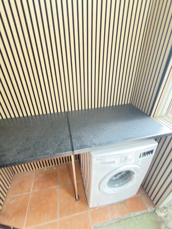 Utility room with washing machine, work counter, wooden stool and corrugated metal walls