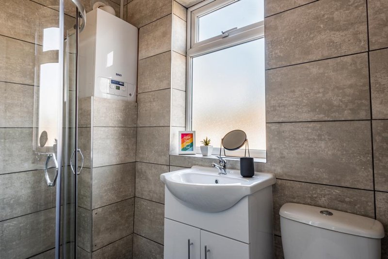 Modern bathroom with shower enclosure, white sink vanity, toilet, and large window