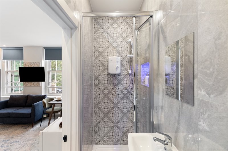 Modern bathroom with walk-in shower, mosaic tiles, glass enclosure and sink