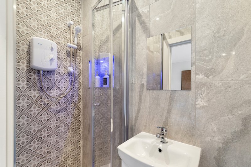 Modern bathroom with walk-in shower, white sink, mirror and hand dryer dispenser