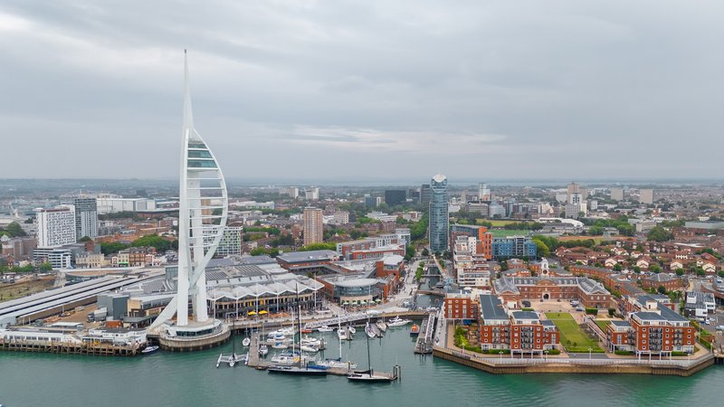 Aerial waterfront view of modern sail-shaped building with harbor, boats, and cityscape