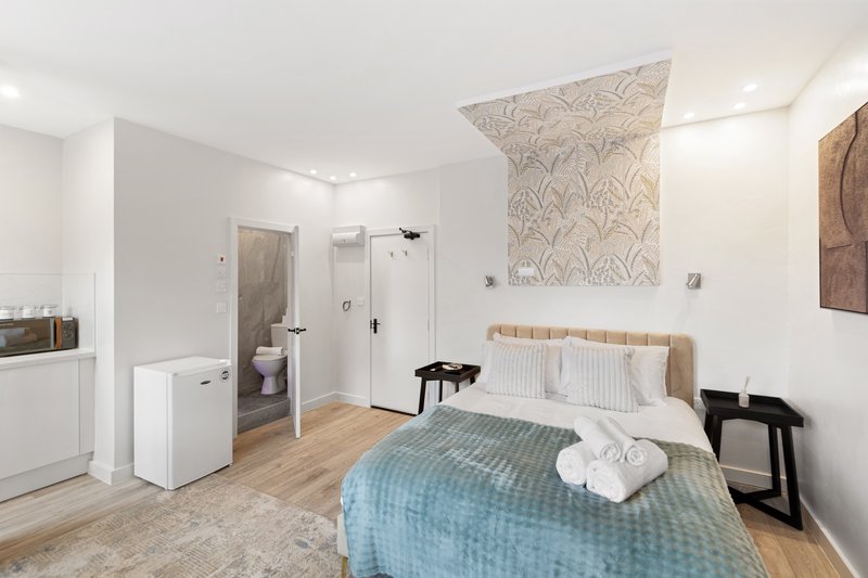 Bright modern bedroom with double bed, en-suite bathroom, wooden flooring and white walls