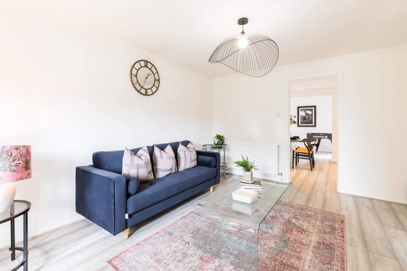 Modern living room with navy sofa, glass coffee table, pendant lamp and wooden flooring