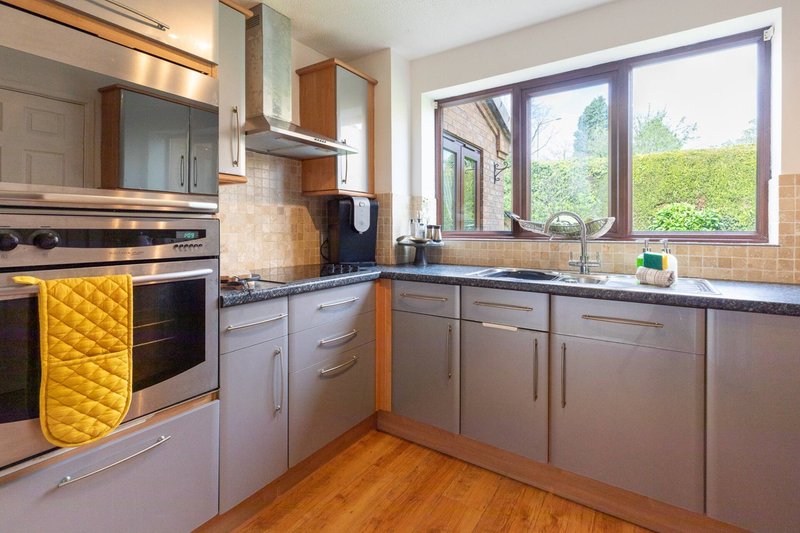 Modern kitchen with gray cabinetry, stainless steel appliances, wooden flooring and garden view