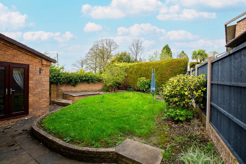 Spacious garden with lawn, hedges, brick building and wooden fencing
