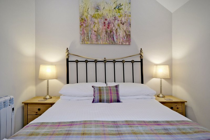 Bedroom with double bed, black metal headboard, wooden nightstands, and wall lamps