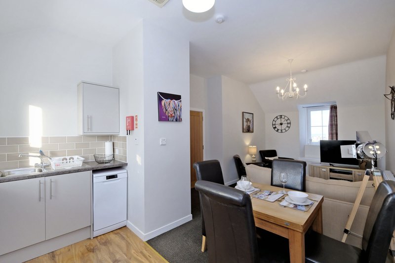 Open-plan kitchen and living area with white cabinetry, dining table, and modern furnishings
