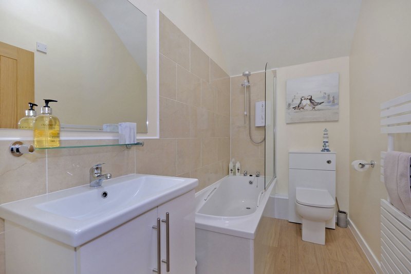 Modern bathroom with white sink, shower cubicle, toilet, and wooden flooring