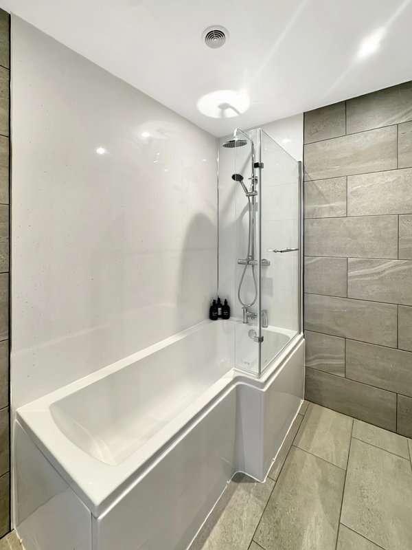 Modern bathroom with white bathtub, glass shower enclosure, and tiled walls