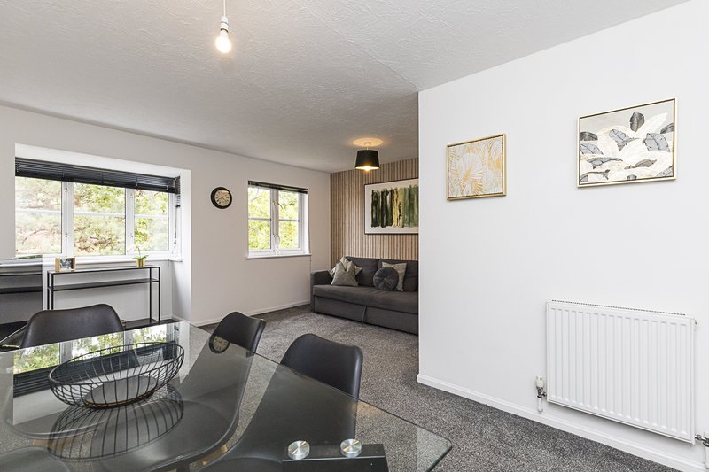 Open-plan living area with dining table, seating nook, windows and wall art