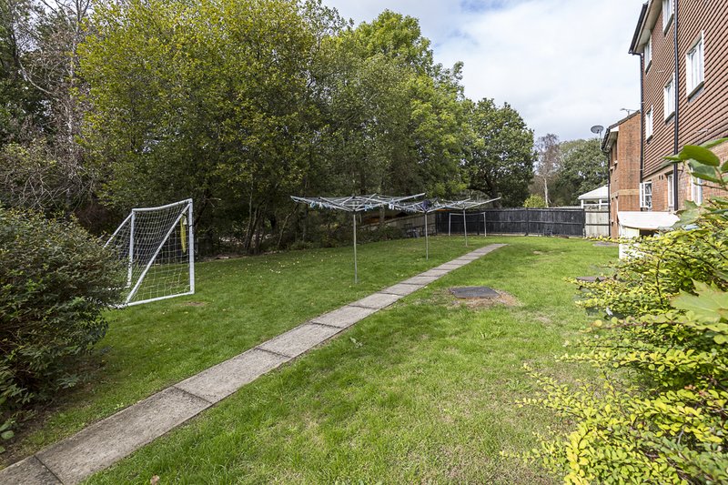 Spacious garden with lawn, paved pathway, goal post and fenced boundaries