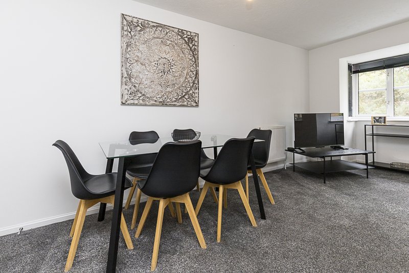 Modern dining area with glass table, black chairs, and wall art in bright room