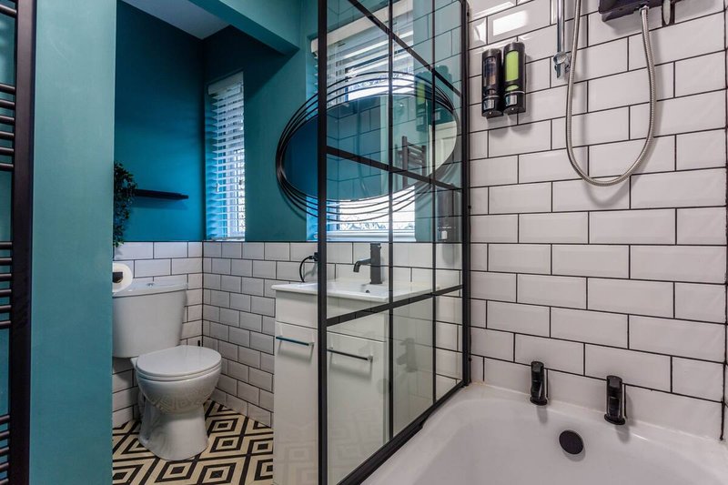 Modern bathroom with white subway tiles, teal walls, walk-in shower and toilet