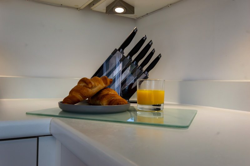 Modern kitchen counter with knife block, croissants, and glass of orange juice