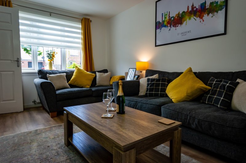 Living room with two dark sofas, yellow cushions, wooden coffee table and framed cityscape artwork