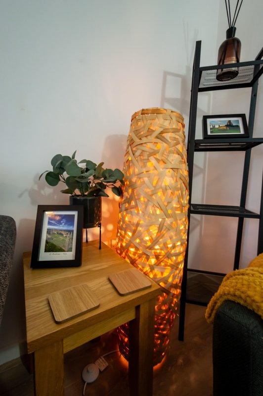 Wooden side table with decorative lamp, potted plant, framed photo and shelving unit
