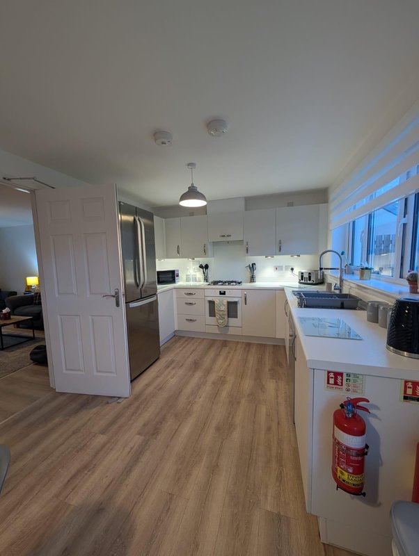 Modern kitchen with white cabinetry, stainless steel appliances, island counter and wooden flooring
