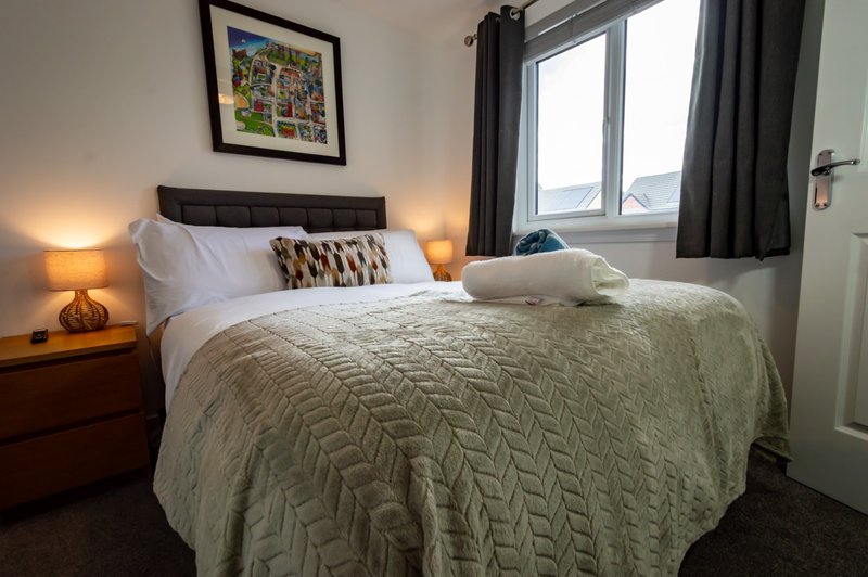 Bedroom with double bed, bedside lamps, framed wall art, and window with curtains