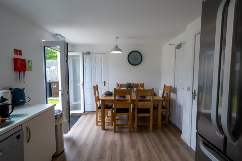 Open-plan kitchen and dining area with wooden table, chairs, and access to garden