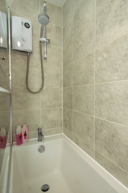 Modern bathroom with walk-in shower enclosure, rainfall showerhead, and white bathtub