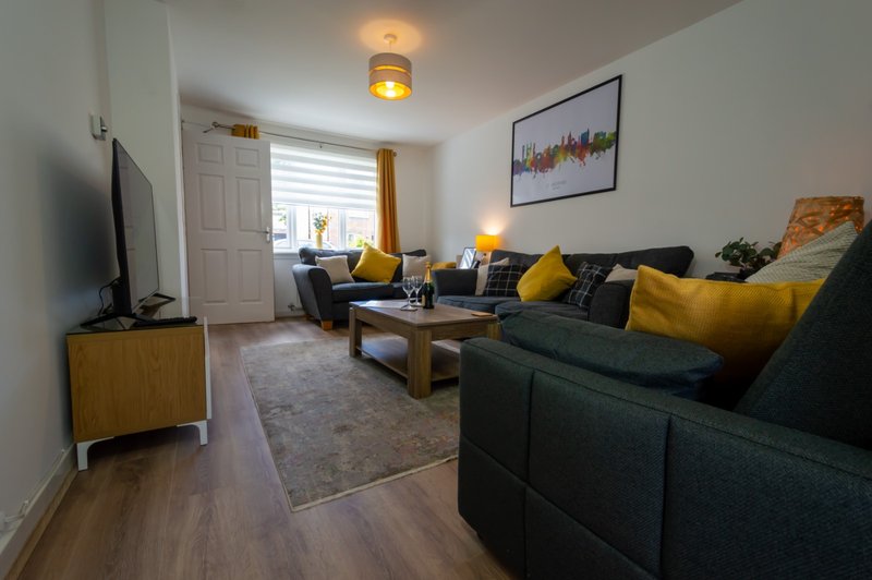 Living room with dark sofa, yellow cushions, wooden coffee table and TV
