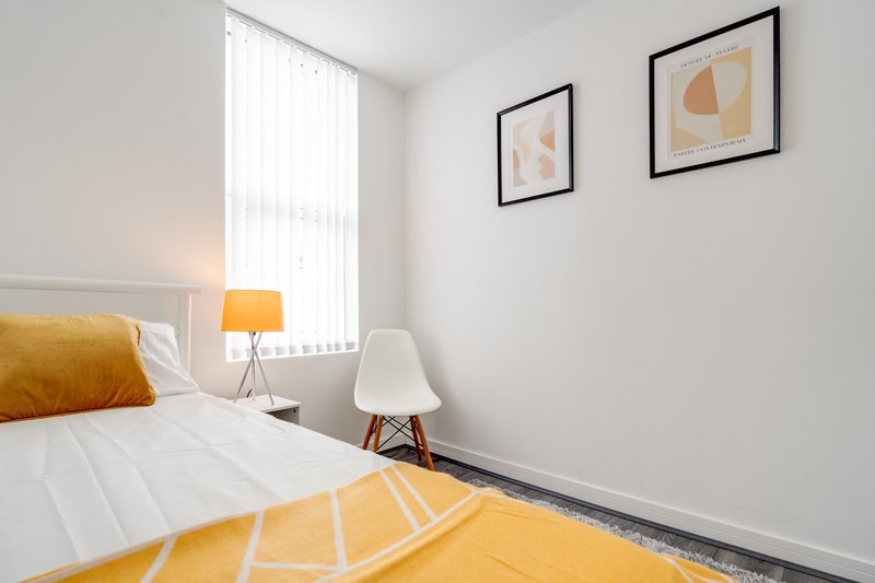 Bright bedroom with double bed, yellow accents, framed wall art and window