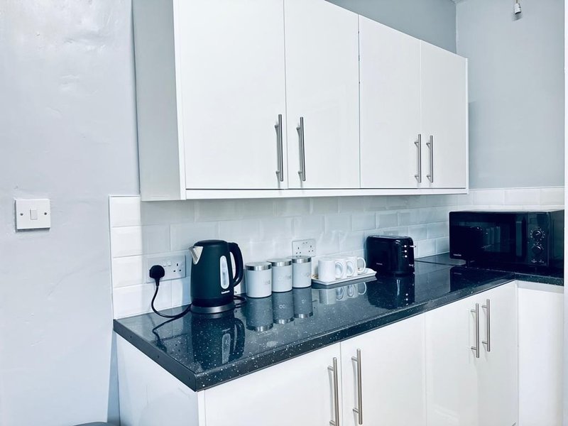 Modern white kitchen with black countertop, appliances and white subway tile backsplash