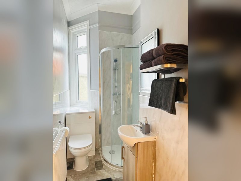 Modern bathroom with shower enclosure, toilet, sink, and towel rack