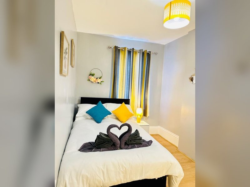 Compact bedroom with single bed, colorful cushions, striped curtains and ceiling light
