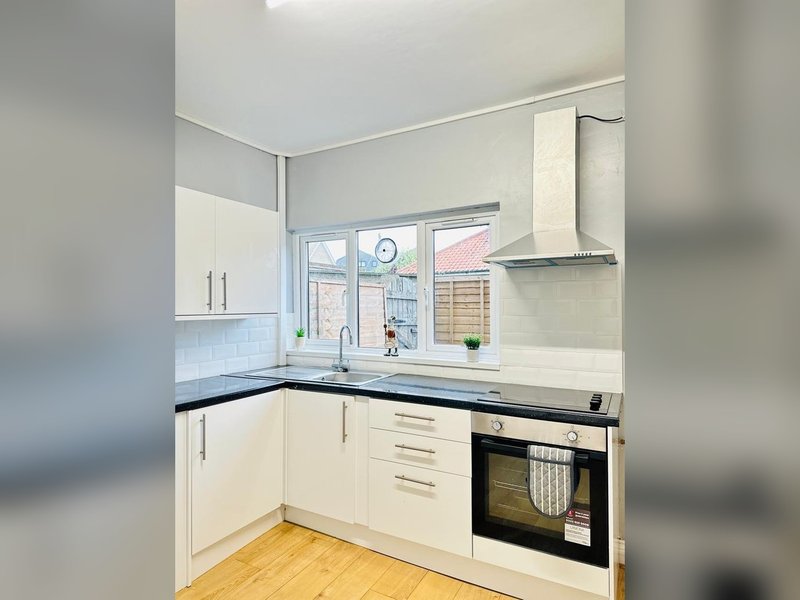 Modern kitchen with white cabinets, black countertop, integrated oven and window view
